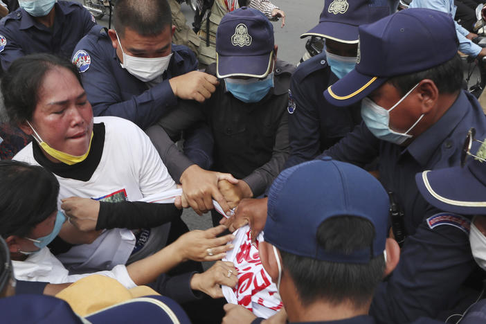 Local security personnel try to grab a banner from supporters of the Cambodia National Rescue Party in front of the Phnom Penh Municipal Court Thursday in Phnom Penh, Cambodia.