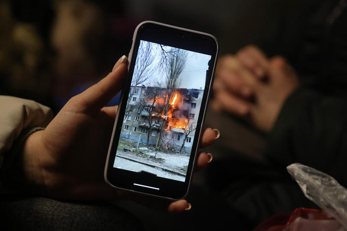 Iryna Holoshchapova, a Ukrainian refugee who fled the embattled city of Mykolaiv, shows a video on her smartphone of an apartment block on fire following a Russian attack.