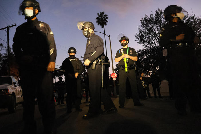 Los Angeles Police Department officers block the street near Echo Park Lake as protesters demonstrate against the removal of a homeless encampment on March 25, 2021, in Los Angeles. Officials asked people living in tents at the park to leave. Police detained 16 journalists reporting on the night's events, arresting two and shooting two others with rubber bullets.