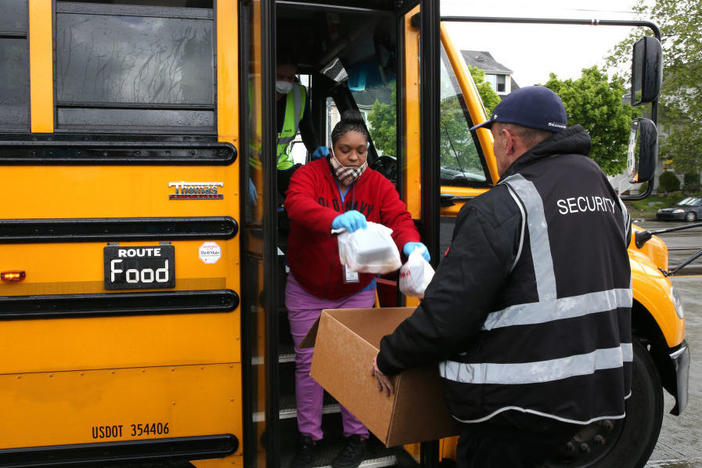Nutritionist Shaunté Fields (center) and bus driver Treva White (behind Fields, on the bus) deliver meals to children and their families in Seattle. When schools closed because of COVID-19, Seattle Public Schools began distributing breakfast and lunch to students through a network of 26 school sites and 43 bus routes five days a week.