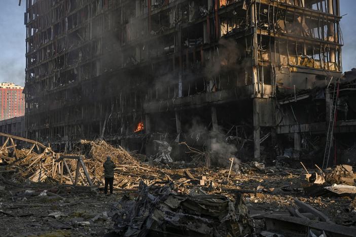 A man stands looking at the burning and destroyed Retroville shopping mall after a Russian attack on the northwest of the Ukrainian capital, Kyiv, on Monday. The high-rise building was hit by a powerful blast that also destroyed vehicles and left a large crater.