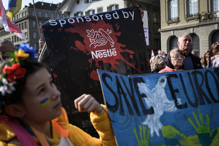 Protesters hold a banner calling out Swiss food giant Nestlé during a demonstration against the Russian invasion of Ukraine next to the Swiss House of Parliament in Bern on Saturday. The company faced criticism in recent days for continuing to do busines in Russia.