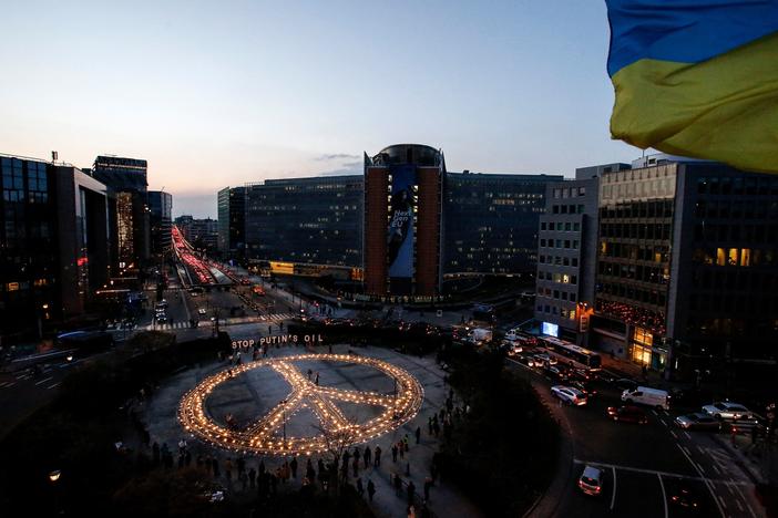 Demonstrators stand around a peace sign during a vigil for Ukraine near the European Union headquarters in Brussels on Tuesday. Activists are calling on EU leaders to impose a full ban on Russian fuel.
