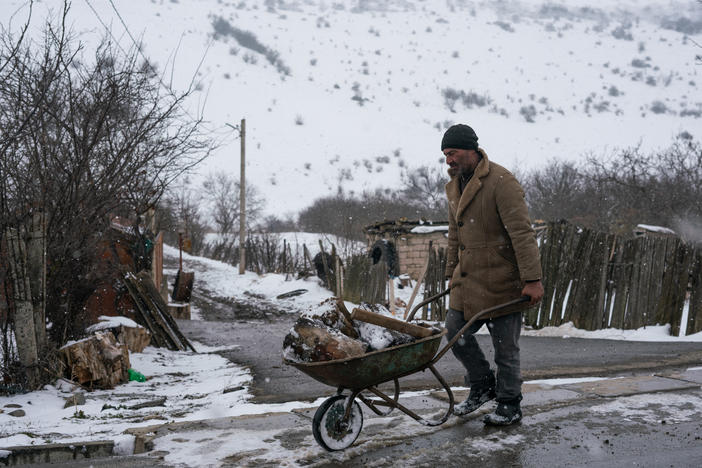 A man pushes a wheelbarrow full of wood on a street in Khurvaleti, a village split in two by the boundary of South Ossetia.