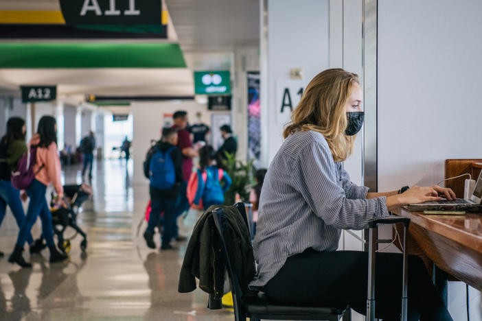 The CEOs of the major U.S. airlines have called on President Biden to end the federal mask mandate for public transportation. Here, a traveler works on a laptop computer at George Bush Intercontinental Airport in Houston on Dec. 3.