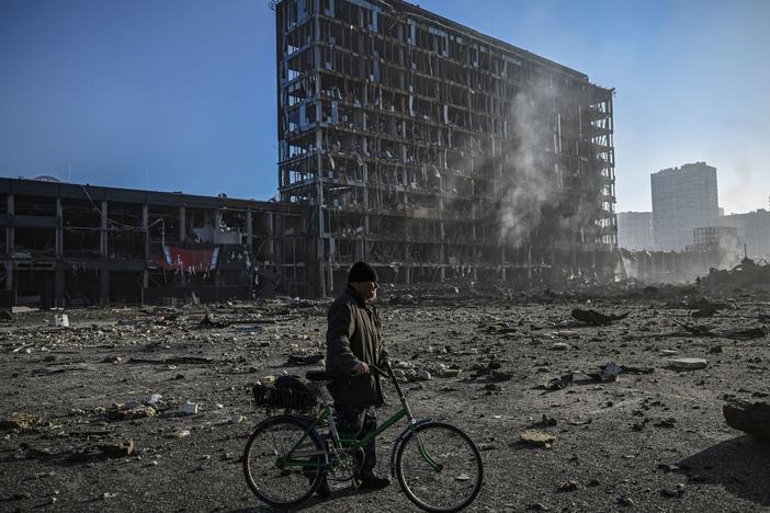 A man with his bicycle walks between debris outside the destroyed Retroville shopping mall in a residential district, after a Russian attack on the Ukrainian capital of Kyiv on Monday.