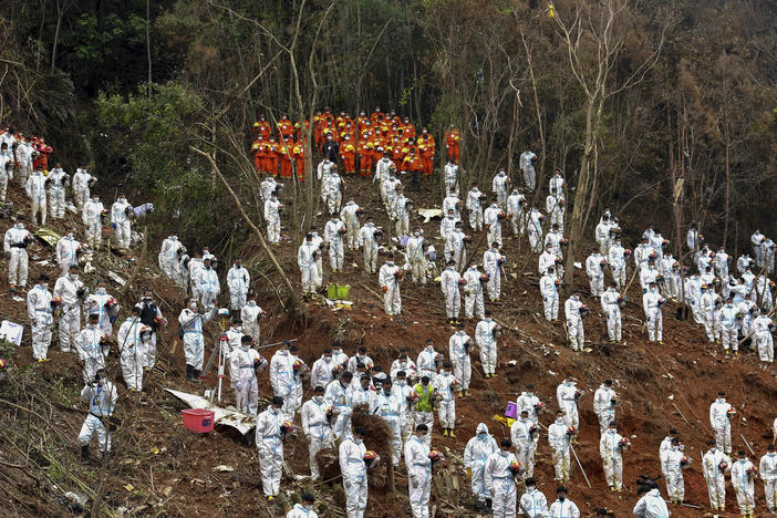 Search and rescue workers pause for a moment of silence for the 132 people killed at the China Eastern flight crash site in Tengxian County on March 27, 2022, in southern China's Guangxi Zhuang Autonomous Region.