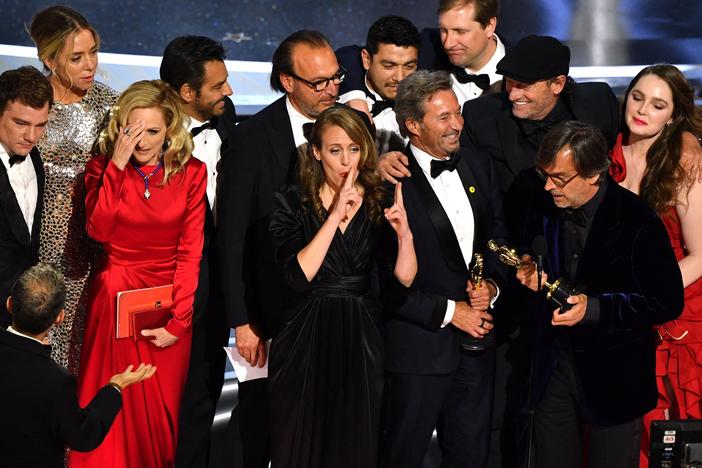 The cast and crew of CODA accept their award onstage.