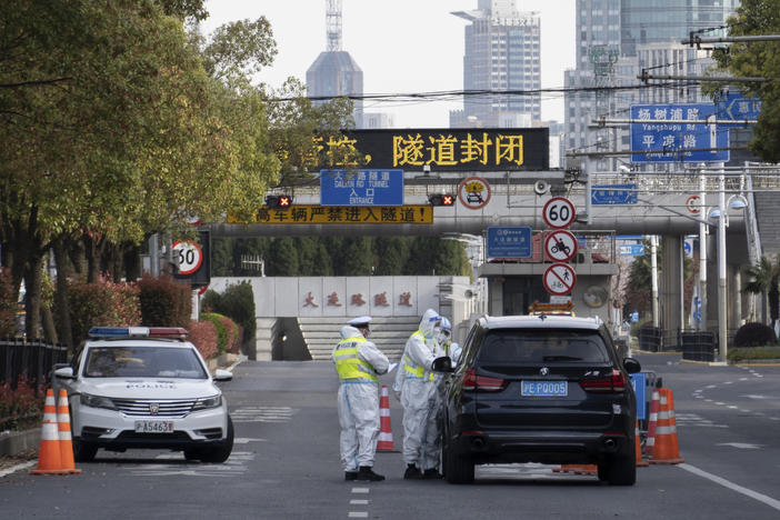 Traffic police wearing protective suits check on a vehicle before an underpass tunnel that has closed following the coronavirus outbreak in Shanghai, China, on Monday.