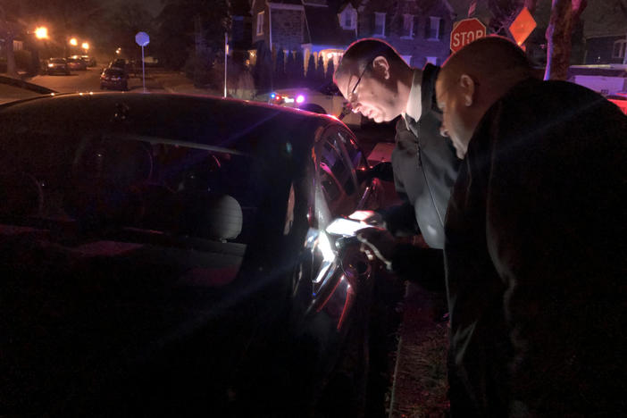 Sgt. Joe Dydak and Lt. Dennis Rosenbaum examine bullet holes in a car. They're part of the Philadelphia Police Department's new citywide team investigating nonfatal shootings.