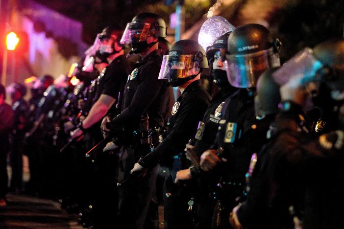 Police form a line as activists and supporters of residents of a homeless encampment protest at Echo Park Lake in Los Angeles late on March 24, 2021.