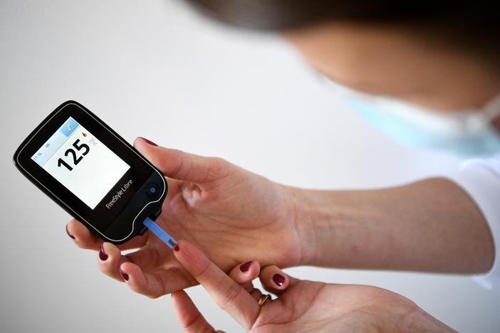 A woman with diabetes uses a glucometer to measure the glycemia in her blood on March 24, 2020.