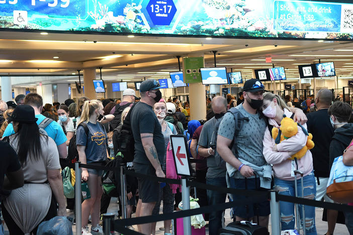 Spring break passengers wait in a TSA security line at Orlando International Airport. While COVID-19 face masks are still required, crowds have increased over last year.