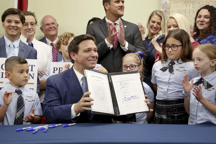 Florida Gov. Ron DeSantis displays the signed Parental Rights in Education, the so-called "Don't Say Gay" bill, flanked by elementary school students during a news conference on Monday at Classical Preparatory school in Shady Hills, Fla.