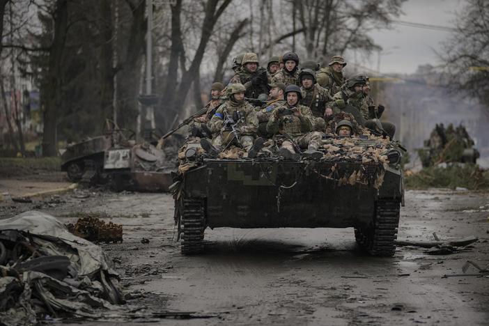 Ukrainian servicemen ride on a fighting vehicle outside Kyiv on Saturday. Russian forces are retreating from the capital's region as they turn their firepower to the south and east.