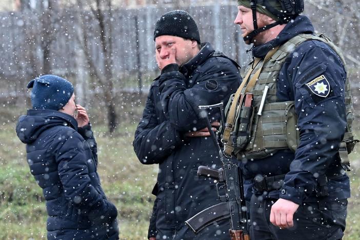 People react as they gather close to a mass grave in the town of Bucha, just northwest of the Ukrainian capital of Kyiv on Sunday.