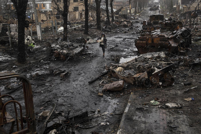 <strong>April 3:</strong> A woman walks amid destroyed Russian tanks in Bucha, on the outskirts of Kyiv.