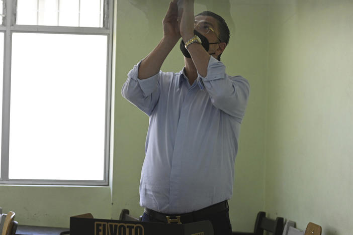 Seen through a glass window, presidential candidate Rodrigo Chaves reacts after marking his ballot during a runoff presidential election, at a polling station, in San Jose, Costa Rica, on Sunday.