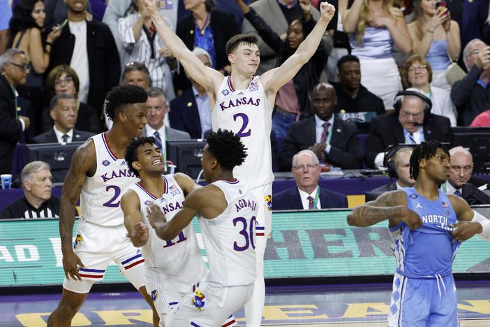 K.J. Adams #24, Remy Martin #11, Ochai Agbaji #30, and Christian Braun #2 of the Kansas Jayhawks celebrate after defeating the North Carolina Tar Heels 72-69 during the 2022 NCAA Men's Basketball Tournament National Championship in New Orleans.