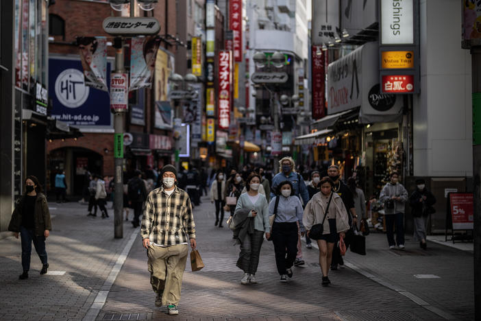 A man wearing a face mask walks along a shopping street on March 25, 2022, in Tokyo.