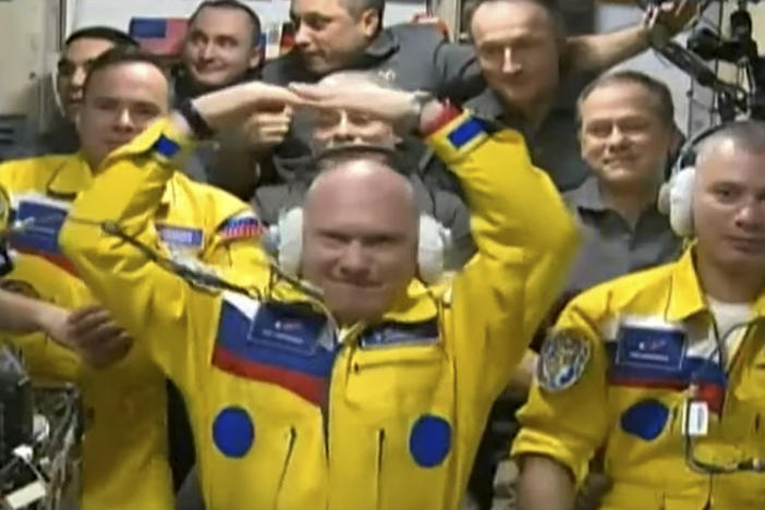 In this photo taken from video footage released by the Roscosmos Space Agency, three Russian cosmonauts sport yellow spacesuits upon arriving on the International Space Station. A NASA astronaut now says it was not in support for Ukraine, but for the Russians' university school colors.