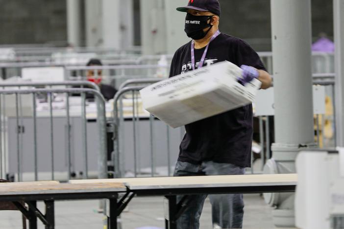 An election worker in Atlanta carries a bin of ballots to be scanned on Jan. 5, 2021, during Georgia's U.S. Senate runoff elections.