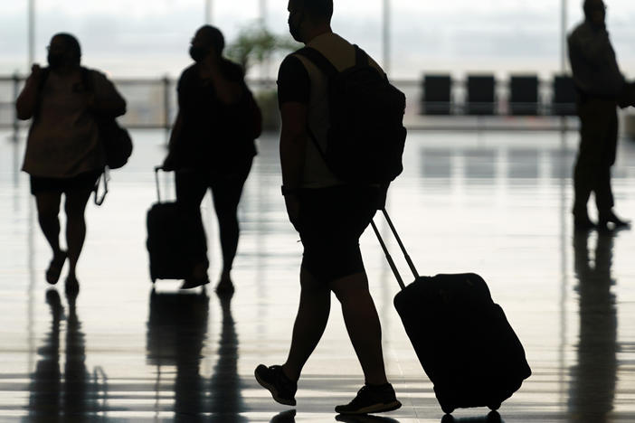 Travelers move through Salt Lake City International Airport on Aug. 17, 2021. The Federal Aviation Administration said Friday that it's seeking record civil fines against two passengers who assaulted other people on flights last summer.