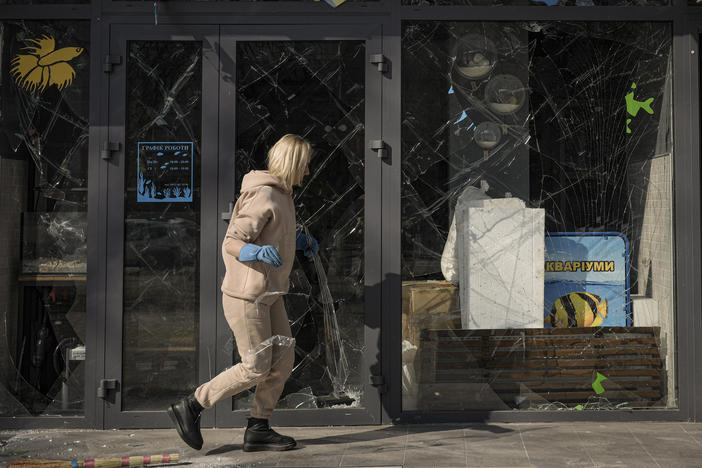 A woman removes pieces of broken glass from a shop window after a bombing in Kyiv, Ukraine, on March 23.