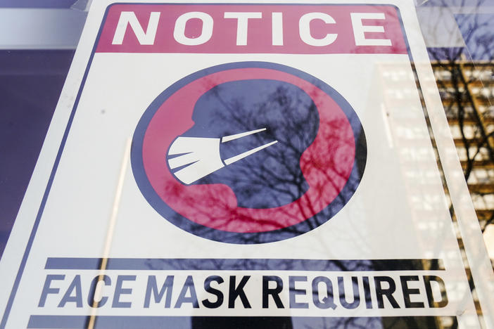 A sign requiring masks as a precaution against the spread of the coronavirus is taped on a storefront in Philadelphia on Feb. 16.