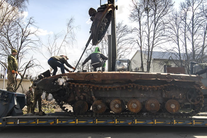 Workers remove a destroyed Russian military tank from the road near Andriivka, a village close to Kyiv, Ukraine, on Monday.