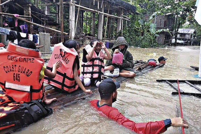 Residents are evacuated by rescuers in a flooded village in Panitan, Panay island, Philippines on Tuesday. Heavy rains caused by a summer tropical depression killed at least a few dozen people in the central and southern Philippines, mostly due to landslides, officials said.