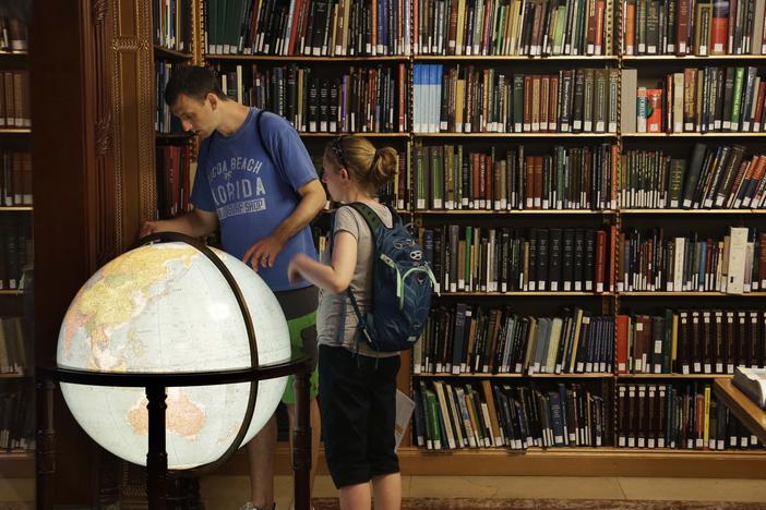 Visitors look at a globe in the map division at the main branch of the New York Public Library in New York. The library announced an effort this week to make commonly banned books available through their app.