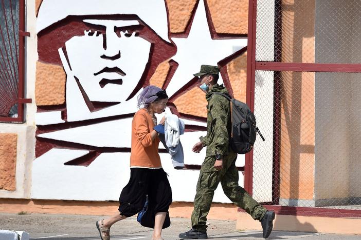 A soldier and a woman walk past the headquarters for Russian troops in September 2021 in the town of Tiraspol, in Trans-Dniester, a pro-Russian region that declared independence from Moldova but is internationally unrecognized. Russia has stationed 1,500 soldiers in the area.