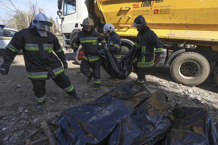 Crews carry body bags as they search for remains and remove debris in the Borodyanka area outside Ukraine's capital of Kyiv on Friday.