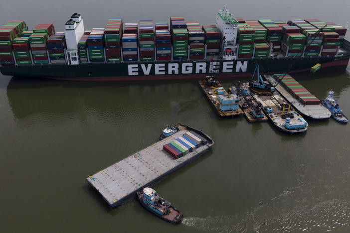 Tugboats, bottom, align a barge near the container ship Ever Forward, top, which ran aground last month, as workers remove containers from it in efforts to lighten the load and refloat the vessel on  April 13.