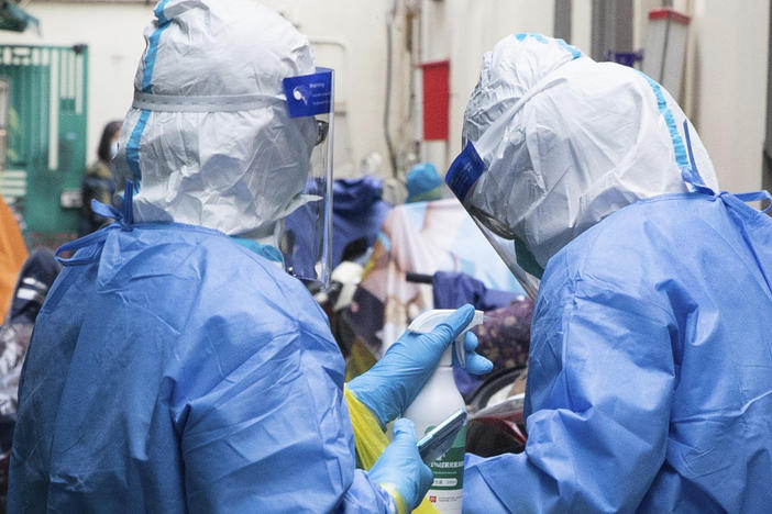 In this photo released by China's Xinhua News Agency, a medical worker disinfects another after taking samples for COVID-19 tests in a residential area in Shanghai, China, Saturday, April 16.