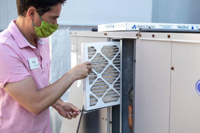 Mark Marston slides a higher-quality air filter back into an upgraded HVAC system in Portland, Maine. The new system can bring in about 30% more outside air.