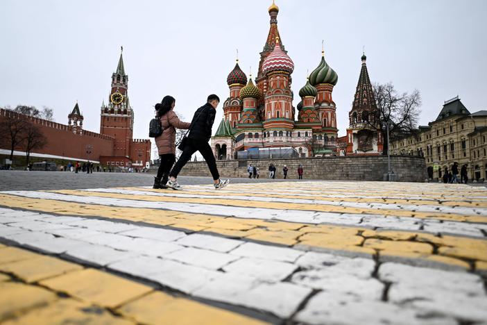 A couple walk in front of the Kremlin's Spasskaya Tower and St Basil's cathedral in downtown Moscow. While 80% of poll respondents say they support Russia's military, some have mixed feelings.