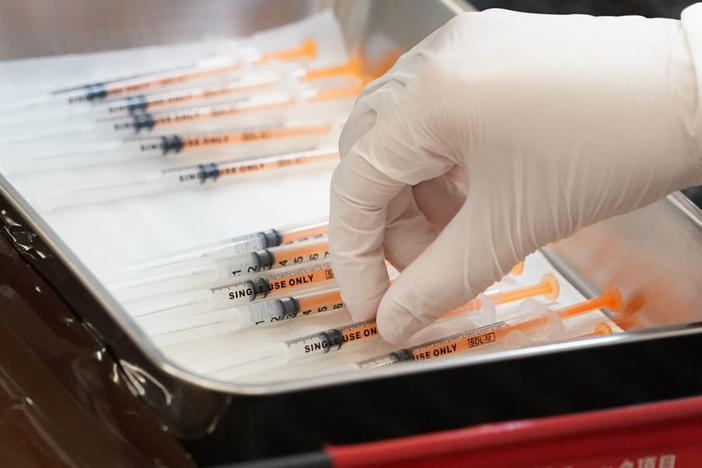 A health care worker prepares the current COVID vaccine booster shots from Moderna in February. The company says a bivalent vaccine that combines the original strain with the omicron strain is the lead candidate for a fall vaccination campaign.