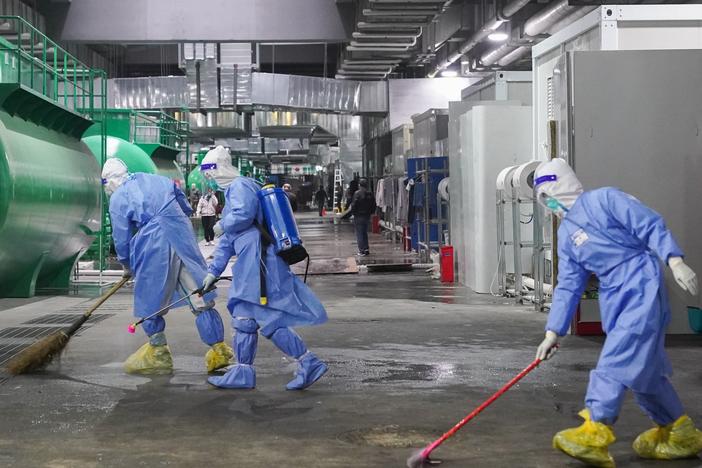 Workers clean and disinfect the floor at the National Exhibition and Convention Center NECC, the largest makeshift hospital, in Shanghai. Many jobs in these temporary facilities are drawn from the pool of unemployed migrant workers.