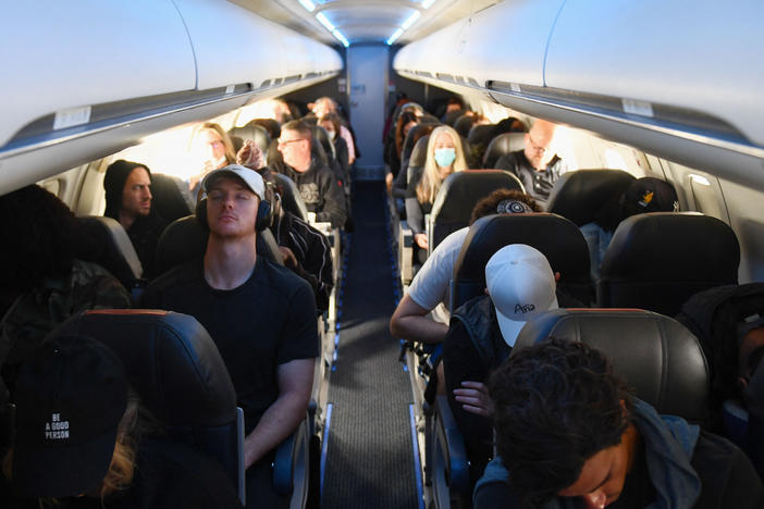 Airline passengers, some not wearing face masks following the end of the federal mask mandate, sit during a American Airlines flight operated by SkyWest Airlines from Los Angeles International Airport to Denver, on Tuesday.