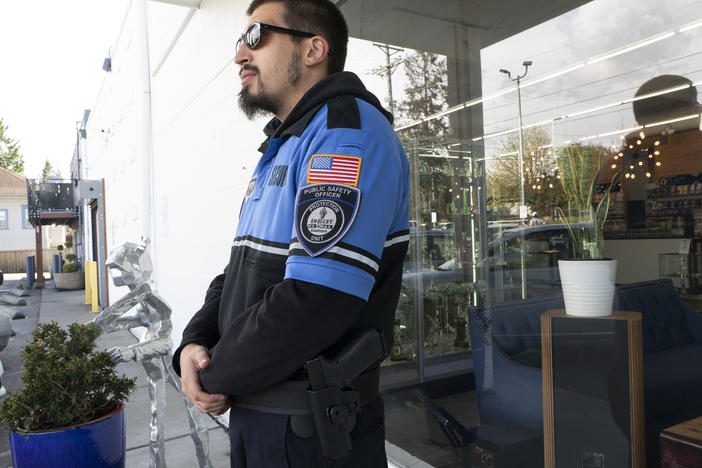 Security guard Austin MacMath wears a gun on his belt while working outside Mary Mart, a marijuana store in Tacoma, Wash., on Tuesday.