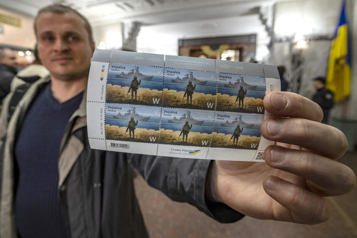 A Ukrainian man holds a set of stamps commemorating the Snake Island soldiers who responded to Russian troops' calls to surrender with a few choice words: "Russian warship, go f*** yourself!"