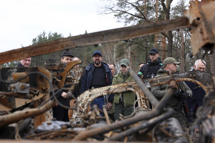 In this image provided by the European Council, European Council President Charles Michel, center, looks at destroyed vehicles as he is given a tour of the region of Borodyanka, Ukraine, Wednesday, April 20, 2022.