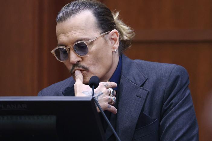 Actor Johnny Depp looks at a defense exhibit on a computer monitor Thursday, during his defamation trial against his ex-wife Amber Heard.