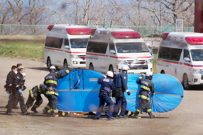 Firefighters transfer a rescued person in Shari, in the northern island of Hokkaido on Sunday.