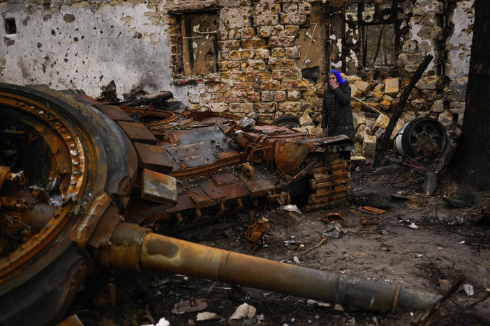 Valentyna Sherba, 68, stands next to a Russian tank in the backyard of her father's home, both destroyed, in the aftermath of a battle between Russian and Ukrainian troops on the outskirts of Chernihiv, northern Ukraine, Saturday, April 23, 2022.