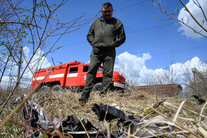 A resident looks at shards of twisted metal from a Russian rocket in undergrowth near a train line near Lviv, Ukraine, on Monday. The head of Ukrainian Railways said five rail facilities had been attacked by Russia Monday morning, including a substation supplying power to overhead lines, in Krasne, near Lviv.