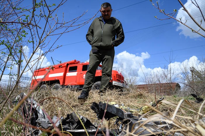 A resident looks at shards of twisted metal from a Russian rocket in undergrowth near a train line near Lviv, Ukraine, on Monday. The head of Ukrainian Railways said five rail facilities had been attacked by Russia Monday morning, including a substation supplying power to overhead lines, in Krasne, near Lviv.