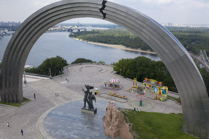 People walk in a city park around a Soviet-era monument in Kyiv, Ukraine, in June 2020.